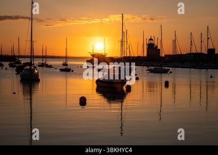 Wunderschöner Sonnenuntergang über dem Hafen mit Booten, die sich anmutig im ruhigen Wasser spiegeln Stockfoto