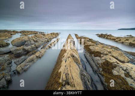Eine ruhige Küstenlandschaft mit Felsvorsprüngen während der wunderschönen Abenddämmerung Stockfoto
