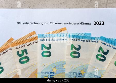 Papierformular für die Steuererklärung im Jahr 2023. Einkommensteuererklärung und Einkommen in Euro-Geldscheinen. Steuer in Deutschland. Stockfoto