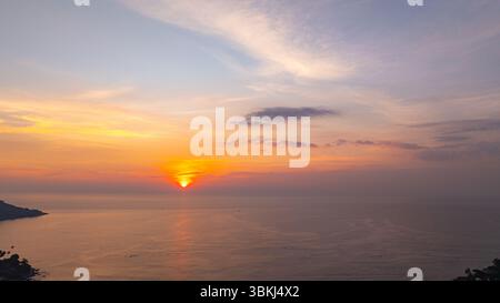 Ein atemberaubender Blick aus der Luft auf den Kata Beach in Phuket, Thailand, während des Sonnenuntergangs. Das Bild zeigt die Küste, kleine Inseln und üppig grüne hil Stockfoto