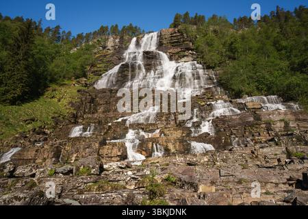 Ein majestätischer mehrstöckiger Wasserfall in den Bergen Norwegens, der Felsvorsprünge herunterfließt. Eine malerische skandinavische Landschaft auf einem klaren, sonnigen Sommer d Stockfoto