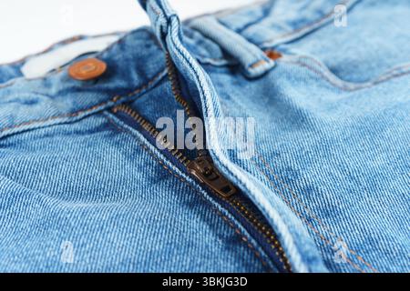 Makrofoto einer blauen Jeans mit Knopf und Reißverschluss aus Kupfer. Sichtbare Stoffstruktur und Nähte. Ideal für Mode, Kleidung und Textilien Stockfoto