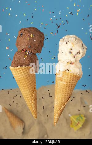Schokoladen- und Vanilleeis in Waffeln vor blauem Hintergrund mit Streuseln Stockfoto