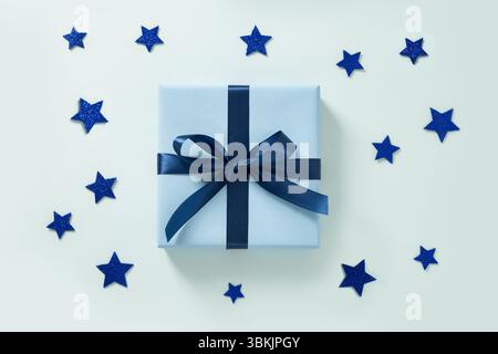 Blaue Geschenkbox und blaue Sterne auf blauem Hintergrund. Grußkarte. Blick von oben. Flache Lagen. Amerikanischer Unabhängigkeitstag. Alles Gute Zum Labor Day Stockfoto