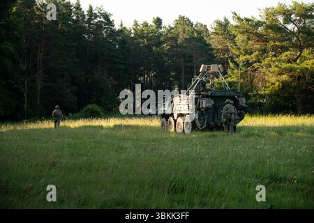 US-Soldaten, die dem 3. Geschwader, 2. Kavallerie-Regiment zugewiesen sind, führen einen Stryker in die Verheimlichung während des Projekts Flytrap im Joint Multinational Readiness Center, Hohenfels Training Area, Hohenfels, Deutschland, 20. Juni. 2025. die Soldaten montierten ein kognitives Radar EchoShield über dem Stryker, das Frequenzen von Drohnen in der Nähe erfasste und Soldaten der Bodenstreitkräfte Echtzeit-Standortdaten auf ihren Endnutzergeräten zur Verfügung stellte. (Foto der US-Armee von SPC. Elijah Magaña) Stockfoto