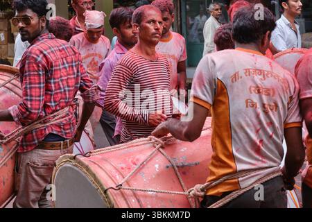 Eine Gruppe von Trommlern, die mit rotem gulal (Gulaal) Pulver bedeckt waren, während einer Prozession während des Ganesh Chaturthi (Ganesh Festival) in Mumbai, Indien Stockfoto