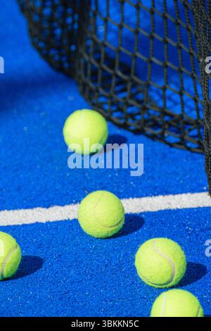 Nahaufnahme der gelben Tennisbälle neben dem Netz auf einem blauen Platz. Stockfoto