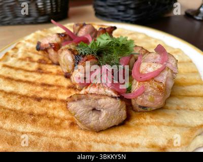 Brötchen gegrilltes Fleisch mit eingelegten Zwiebeln auf Pfannkuchen, Pita. Traditionelle asiatische Küche. Lebensmittel und Produkte. Stockfoto