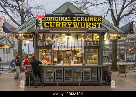 Street-Food-Stand in Berlin, an dem Original Berliner Currywurst verkauft wird, wo Gäste bestellen und verschiedene Getränke im Kiosk im Freien ausgestellt werden. Berlin, Stockfoto