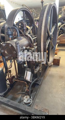 Detaillierte Ansicht eines Vintage-Motors mit großen Metallrädern, Rohren und verschiedenen mechanischen Komponenten auf einem Metallrahmen. Stockfoto