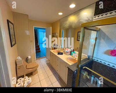 Geräumiges Bad mit zwei Waschbecken, Duschkabine und ordentlicher Einrichtung. Stockfoto