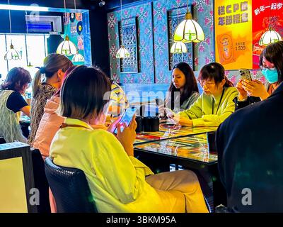 Taipei, Taiwan, Gruppe Junge Leute, sitzen am Tisch, schauen auf Smartphones, lokales Hong Kongese Restaurant, 'Jiu Long Bing Shi', 'Kowloon Cafe' Stockfoto
