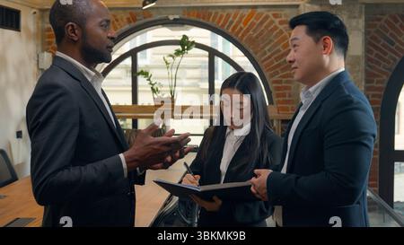 Afroamerikanischer Mann Geschäftsmann spricht mit koreanischen asiatischen männlichen Kollegen zwei Männer multirassische Geschäftsleute Teamwork Zusammenarbeit Japanisch Chinesisch Stockfoto