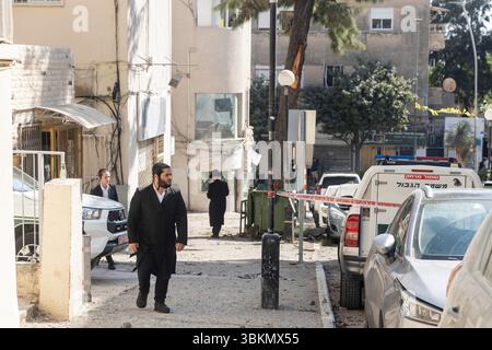 Haifa, Israel, 22. Juni 2025 ein Ultra-orthodoxer jüdischer Mann läuft an einer abgesperrten Straße vorbei. Eine iranische Rakete trifft auf einen Brunnen und ein Gebäude in der Werbung Stockfoto