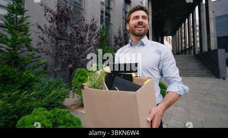 Glückliches Singen lächelnd Gehen in Stadt Mann Geschäftsmann männlicher Kerl Geschäft entlassen Büro beenden Firma arbeiten halten Tragen Entlassungsbox neu Stockfoto