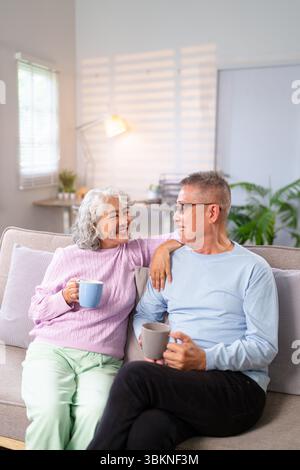 Ein älteres asiatisches Paar teilt einen friedlichen Moment zu Hause und genießt Kaffee in einer entspannten Atmosphäre. Sie sind das Bild von Liebe und Glück in reti Stockfoto