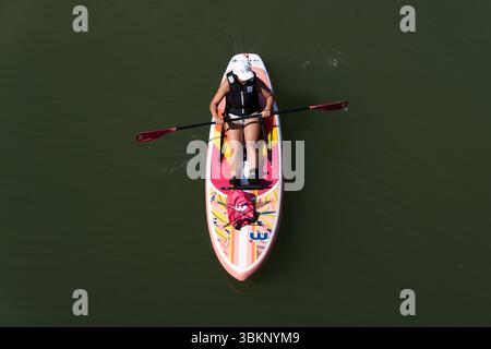 Mainz, Rheinland Pfalz, Deutschland. Juni 2025. Eine Frau reitet während einer Hitzewelle in Mainz auf einem Stand-Up-Paddleboard auf dem Rhein. (Kreditbild: © Matias Basualdo/ZUMA Press Wire) NUR REDAKTIONELLE VERWENDUNG! Nicht für kommerzielle ZWECKE! Stockfoto