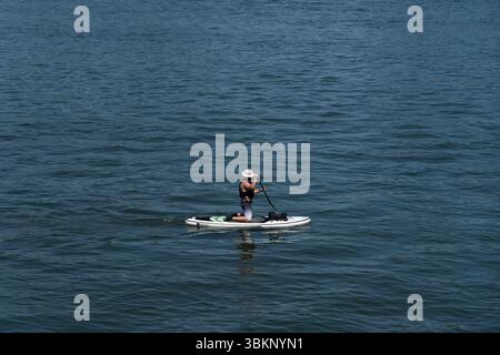 Mainz, Rheinland Pfalz, Deutschland. Juni 2025. Ein Mann reitet während einer Hitzewelle in Mainz auf einem Stand-Up-Paddleboard auf dem Rhein. (Kreditbild: © Matias Basualdo/ZUMA Press Wire) NUR REDAKTIONELLE VERWENDUNG! Nicht für kommerzielle ZWECKE! Stockfoto