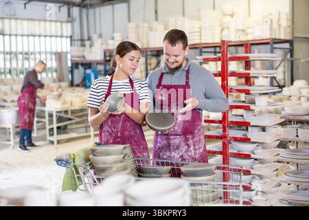 Kollegen in der Keramikwerkstatt diskutieren über eine Reihe von Slipcast-Töpferwaren Stockfoto