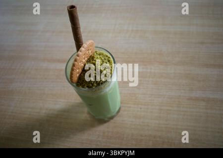 Ein Glas Matcha Green Tea Milchshake, garniert mit einem Keks, einem Keks und einem Waffelstab. Stockfoto