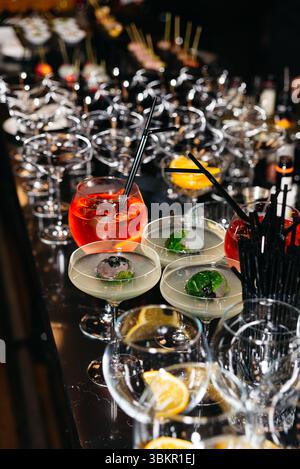 Lebhafte Cocktails und garnierte Getränke werden an einem Hochglanztheken für eine gehobene Veranstaltung oder Party arrangiert. Stockfoto