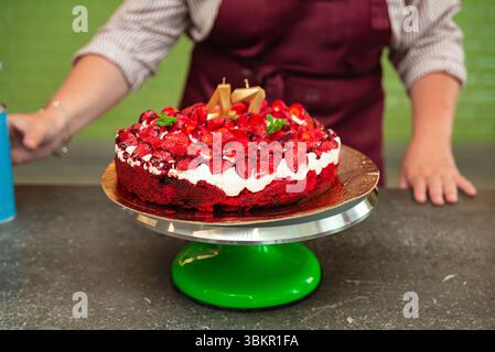 Festlicher Erdbeergeburtstorte mit Schlagsahne und Zahlenkerzen auf einem drehbaren Kuchenständer, perfekt für Feiern und Partys. Stockfoto
