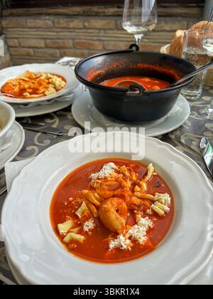 Köstlicher Roter Fisch-Eintopf mit Garnelen und handgemachter Pasta, serviert in einem rustikalen Ambiente mit Brot und Weißwein, die das Wesen des traditionellen Cui einfangen Stockfoto