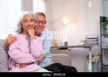 Dieses herzerwärmende Bild fängt das Wesen eines liebevollen älteren asiatischen Paares ein, das das Pensionsleben zu Hause genießt. Sie umarmen sich, zeigen dauerhafte Liebe A Stockfoto