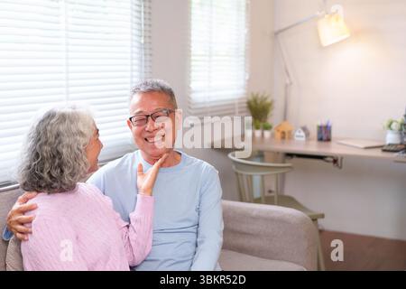 Diese herzerwärmende Szene fängt ein älteres asiatisches Paar in liebevoller Umarmung ein und verkörpert die Schönheit langfristiger Beziehungen, des Ruhestands und des Heims Stockfoto