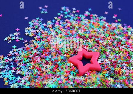 Rosa Stern umgeben von vielen kleinen und bunten Sternen Stockfoto