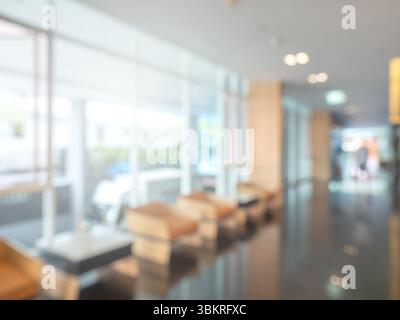 Abstrakter, verschwommener Hintergrund des Luxushotels, Inneneinrichtung der Lobby, Dekoration mit Sofa in der Nähe einer Glaswand, Lichter, Marmorboden. Verschwommen Stockfoto