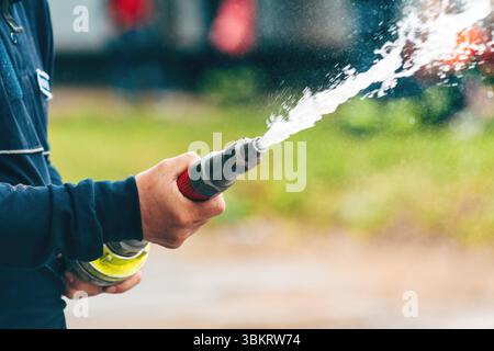 Feuerwehrmann sprüht Wasser aus dem Schlauch, selektiver Fokus Stockfoto