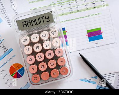 Die Berechnung der Annuität wird auf dem Bildschirm des Rechners angezeigt, der auf Finanzdokumenten mit Diagrammen, Diagrammen und einem Stift platziert wird und Investitionen und Finanzen betont Stockfoto