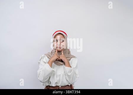 Porträt der schönen jungen asiatischen Muslimin feiert indonesischen Unabhängigkeitstag und schaut ernsthaft über Fragen nach und schaut sich den Kopierraum an Stockfoto