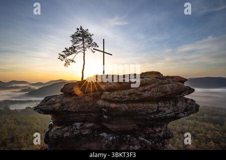 Sonnenaufgang über einer Berglandschaft. Aufgehende Sonne hinter einer Sandsteinklippe im Wald. Nebelbildung im Tal bei Rözenfelsen, Pfälzerwald, Stockfoto