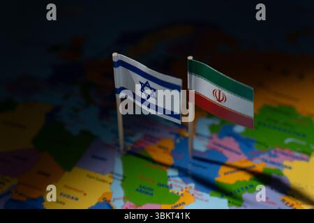 Miniaturflaggen von Israel und Iran werden auf einer verschwommenen Karte gepflanzt. Internationale Beziehungen, Konflikte, Diplomatie und geografische Ausrichtung auf die mittlere EA Stockfoto