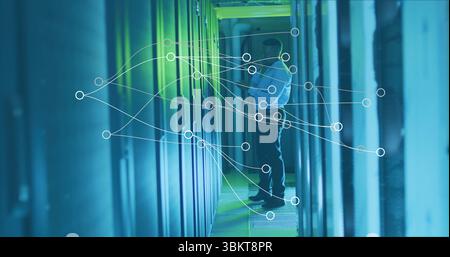 IT-Techniker in weißem Hemd, der Serverschränke im Serverraum mit LED-Netzwerküberlagerung inspiziert Stockfoto