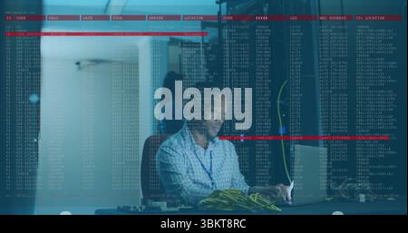 IT-Techniker im karierten Hemd, der Netzwerkausrüstung im Serverraum konfiguriert, mit Laptop und Kabeln Stockfoto