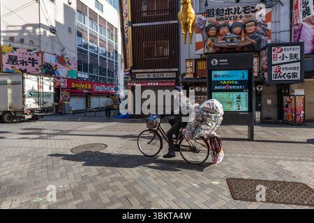 Radfahrer sammeln Müll zum Recycling in Dotonbori, einem Haupttouristenziel im Namba-Viertel von Osaka, Japan. Stockfoto