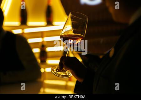 Ein Glas Sekt in den Händen eines nicht erkennbaren Besuchers, der zu einer festlichen Veranstaltung eingeladen wurde, aus nächster Nähe Stockfoto