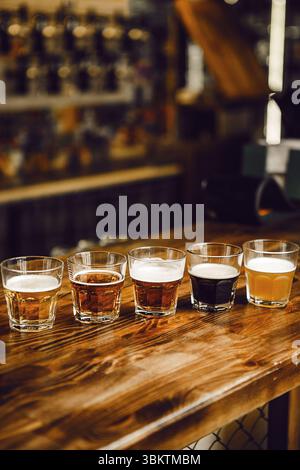 Verschiedene Craft-Biere-Sets werden am Holztheken im Pub-Setting angezeigt Stockfoto