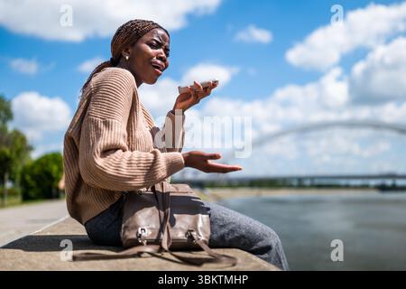 Die junge schwarze Frau spricht am Telefon. Sie ist ängstlich und besorgt. Stockfoto