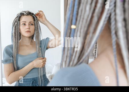 Junge schöne Frau, die in den Spiegel schaut. Stockfoto