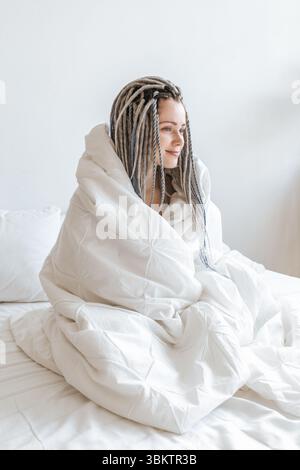 Junge, schöne, glückliche Frau, in eine weiße Decke gewickelt. Stockfoto