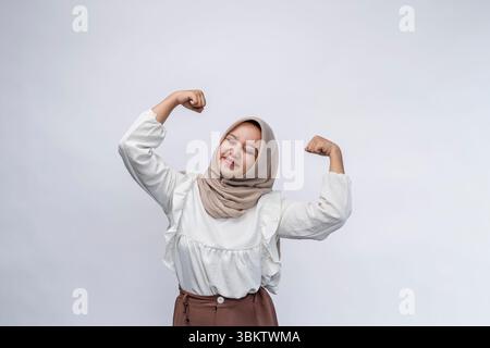 Aufgeregt schöne indonesische muslimische Frau im Hijab feiert Erfolg und blickt auf die Kamera isoliert auf weißem Hintergrund. Menschen religiöse Leben Stockfoto
