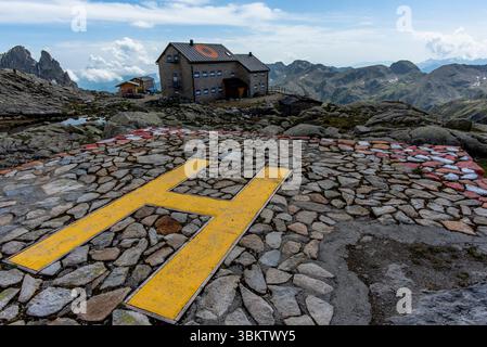 Almhütte zwischen den Granitfelsen des Lagorai-Gebirges mit dem Hubschrauberlandeplatz mit dem H in gelb in Trient Italien Stockfoto