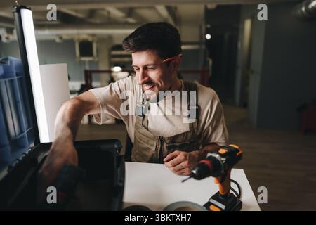 Facharbeiter, der in der Werkstatt während der Abendstunden mit Werkzeugen und Projekten praxisorientierte Übungen durchführt Stockfoto