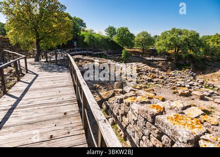 Moderner Holzsteg mit Blick auf die Ruinen der palastartigen Residenz von Troja VI und das westliche Heiligtum in Canakkale, Türkei Stockfoto