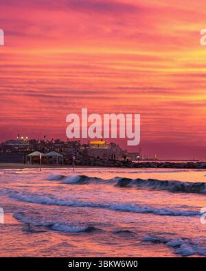Schöner feuriger Sonnenuntergang an einem Mittelmeerstrand in Tel Aviv Israel mit Blick auf die Skyline des alten Yaffo (Jaffa) Stockfoto