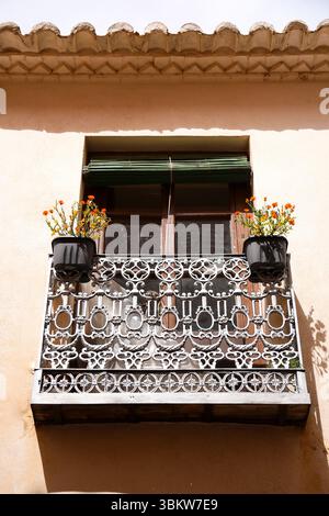 Schmiedeeiserner Balkon mit Topfpflanzen und Holzjalousie in Villanueva de los Infantes, Ciudad Real, Spanien Stockfoto